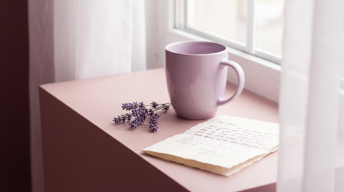 Lilac cup, handwritten note and lavender on a bright blush surface